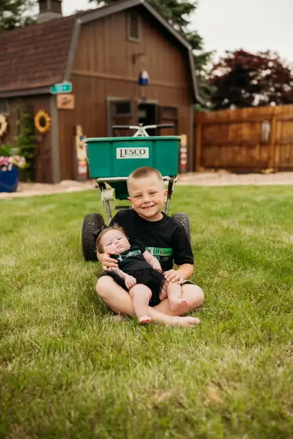 Field of Dreams family with professional lawn care equipment used for seasonal turf improvement